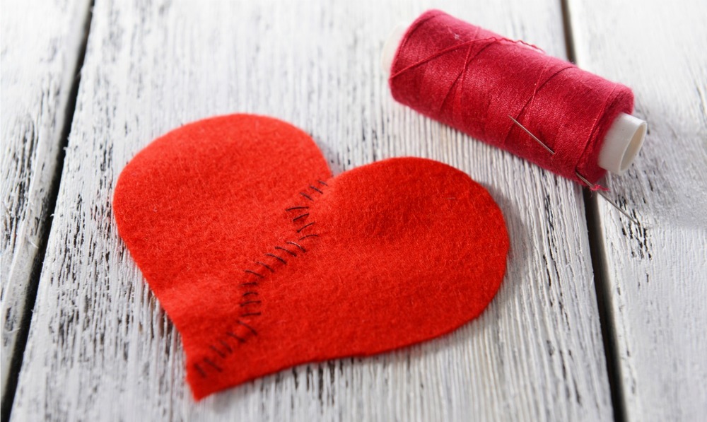Broken heart and thread on wooden background